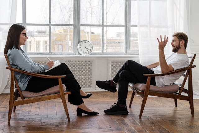 Man and women sitting opposite each other in wooden chairs during a therapy session